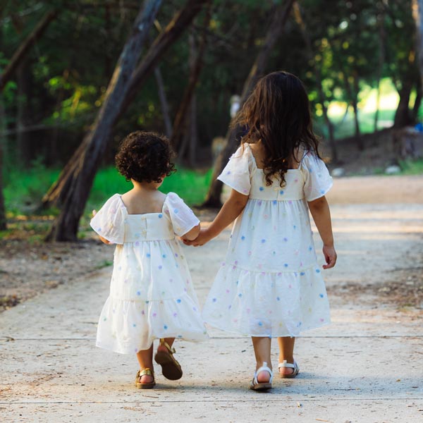 two little girls holding hands walking down sidewalk