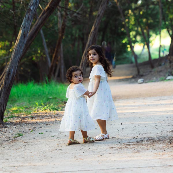 two little girls holding hands walking down sidewalk